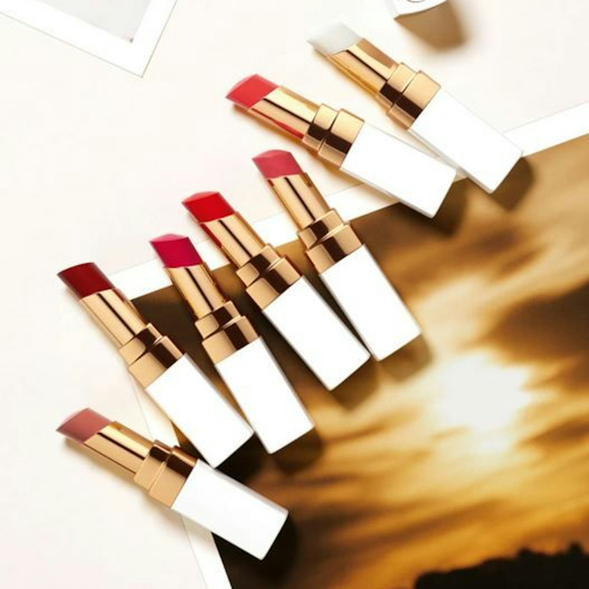 Sieben Lippenstifte von Chanel liegen auf einem neutralen Hintergrund.