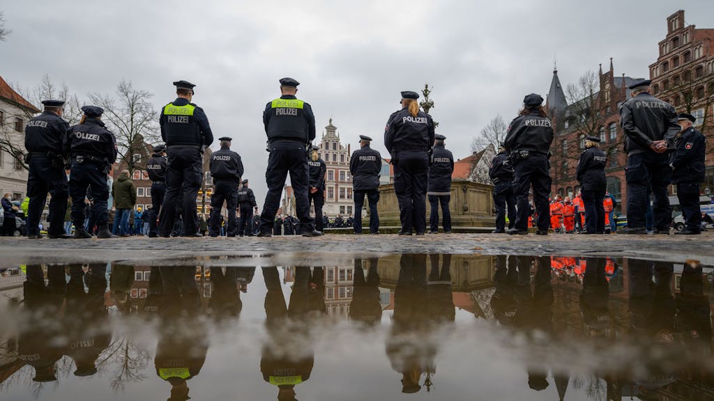 Polizisten stehen auf dem Marktplatz zusammen, um eine Schweigeminute für die in Rheinland-Pfalz getöteten Polizisten abzuhalten.
