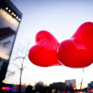 Zwei rote Ballons in Herzform fliegen in der Luft.
