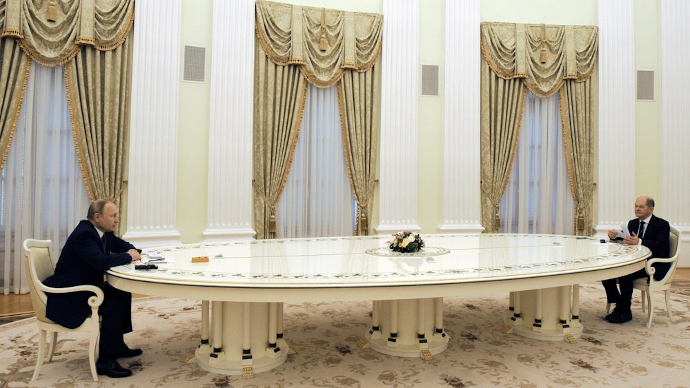 Russlands Präsident Wladimir Putin (l) und Bundeskanzler Olaf Scholz (SPD) sitzen zusammen an einem langen Tisch.