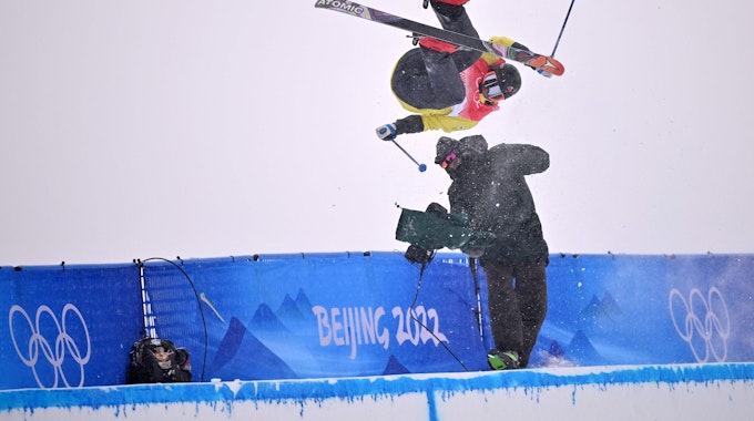 Der Finne Jon Sallinen kracht in der Halfpipe-Qualifikation im Genting Snow Park von Zhangjiakou am 17. Februar 2022 bei einem Sprung mit voller Wucht in einen Kameramann.