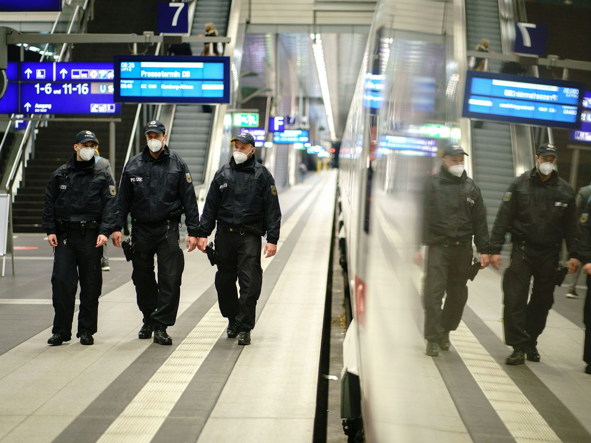 Beamte der Bundespolizei gehen durch einen Bahnhof.