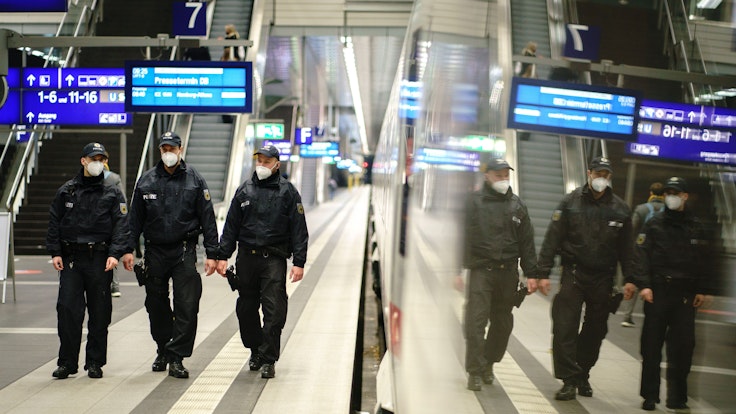 Beamte der Bundespolizei gehen durch einen Bahnhof.