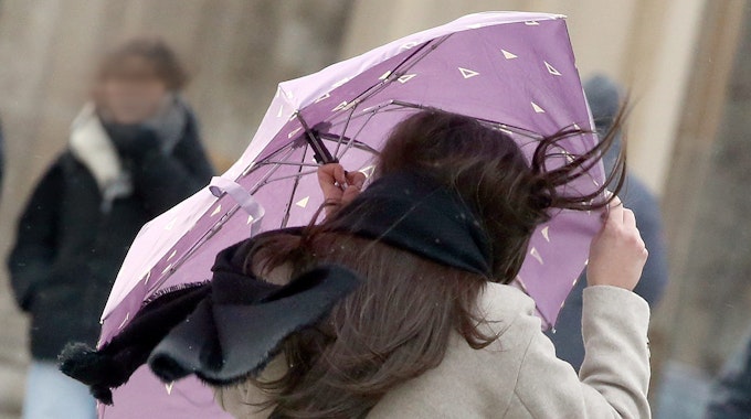 Eine Passantin mit wehenden Haaren sichert am Donnerstag (17. Februar) ihren Regenschirm, während sie sich bei Windstärken bis 100 km/h vor dem Brandenburger Tor entlang spaziert. Ein Experte erklärt, welchen Fehler die Deutschen auf keinen Fall machen sollten.