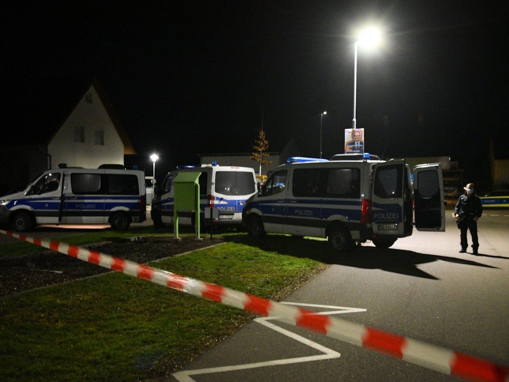 Polizeifahrzeuge in der Nacht vor einem Haus.