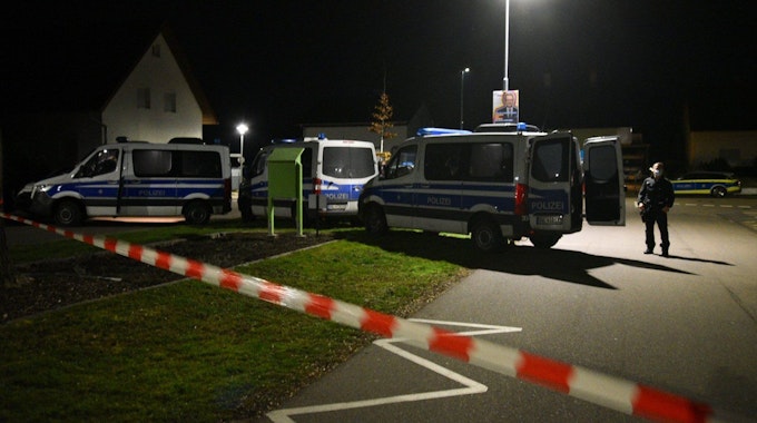 Polizeifahrzeuge in der Nacht vor einem Haus.