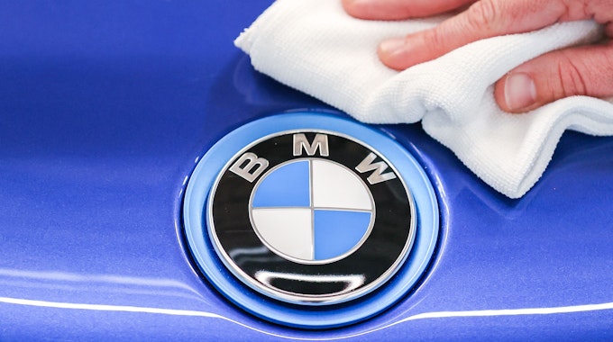 Ein Mitarbeiter von BMW poliert mit einem Tuch das Logo von einem BMW i8.