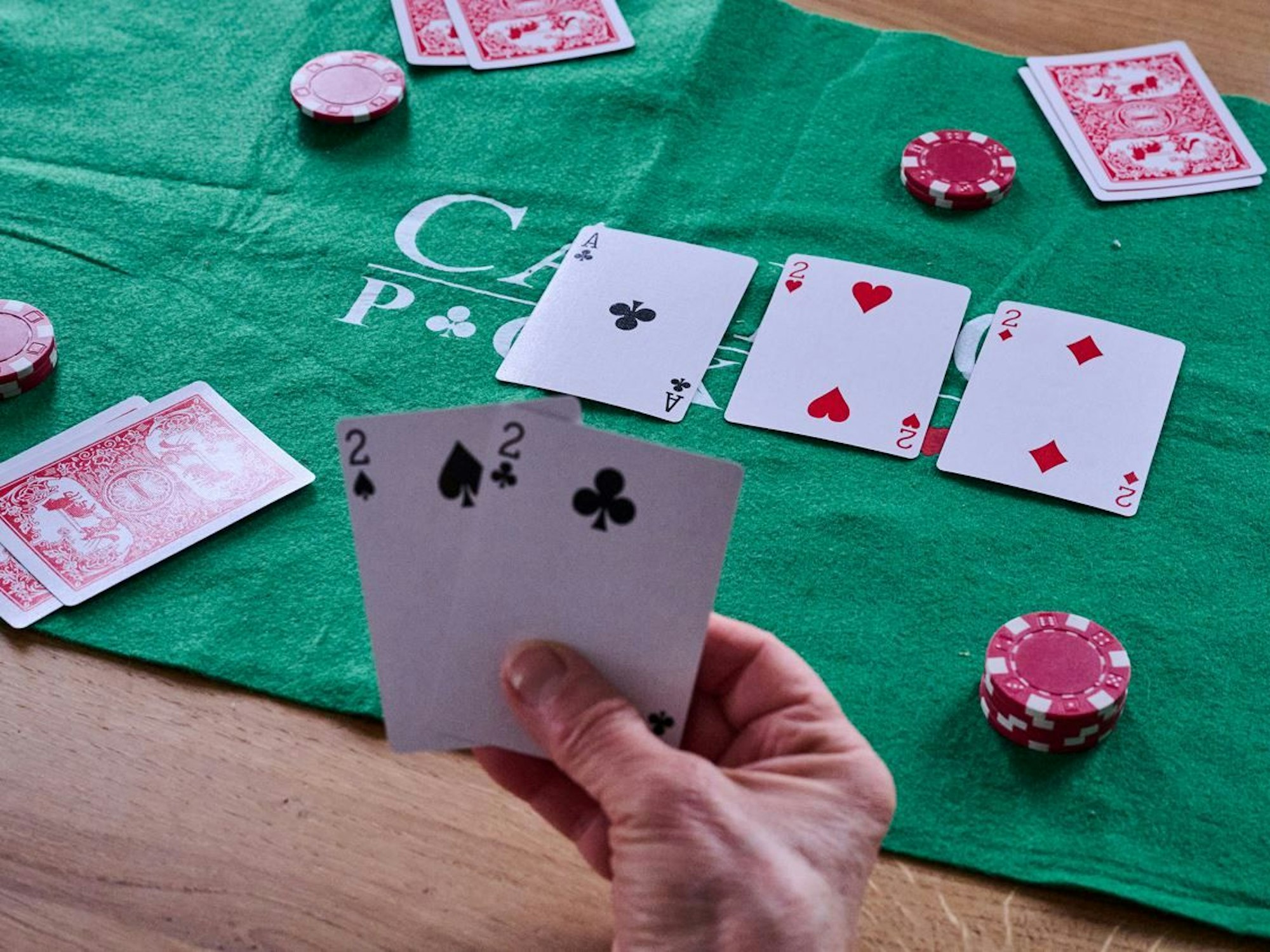 Eine Person hält beim Pokern zwei Zweier in der Hand.