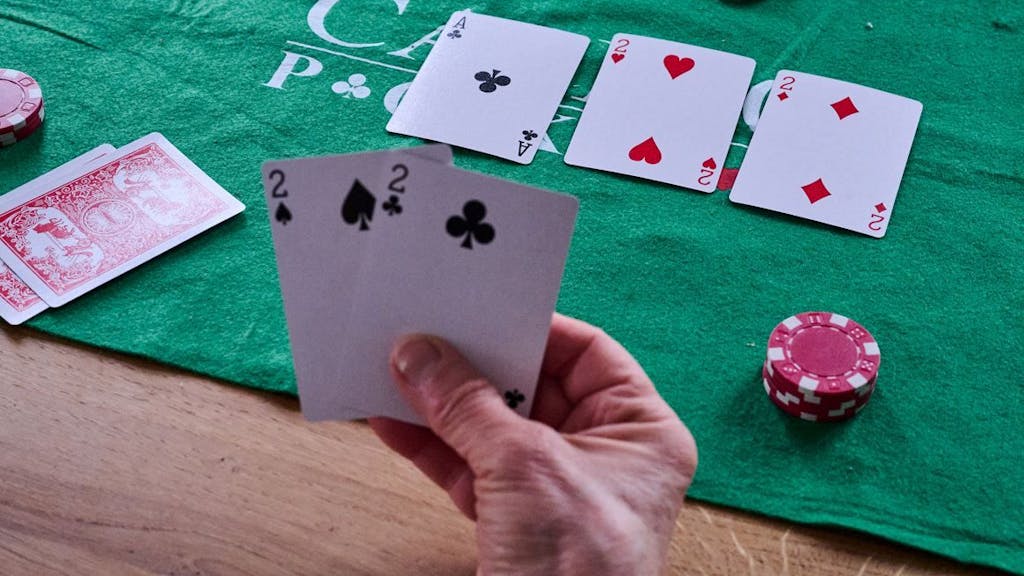 Eine Person hält beim Pokern zwei Zweier in der Hand.