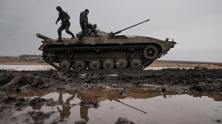 Zwei ukrainische Soldaten stehen während einer Schießübung am 10. Februar auf einem Panzer, der auf einem Feld steht.