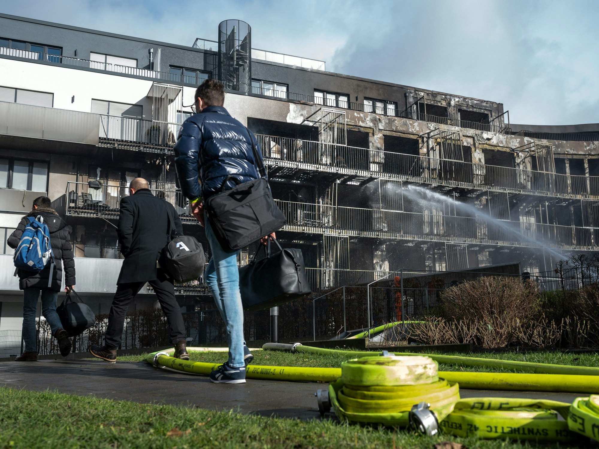 Menschen verlassen das Gelände des ausgebrannten Komplexes in Essen.