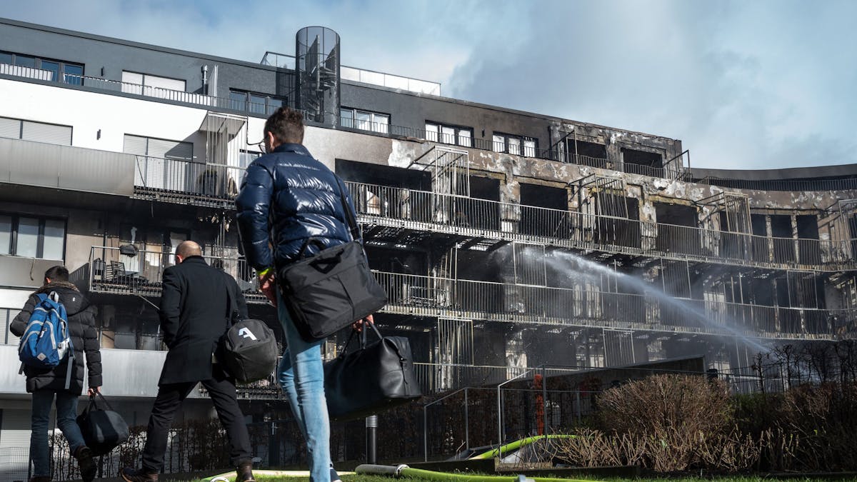 Menschen verlassen das Gelände des ausgebrannten Komplexes in Essen.