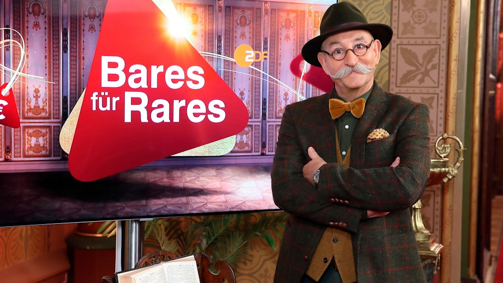 Moderator Horst Lichter steht neben dem Logo der Sendung „Bares für Rares“ (undatierte Aufnahme).