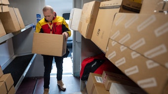 Ein DHL-Mitarbeiter sortiert in seinem Transporter Pakete für die nächsten Zustellungen.