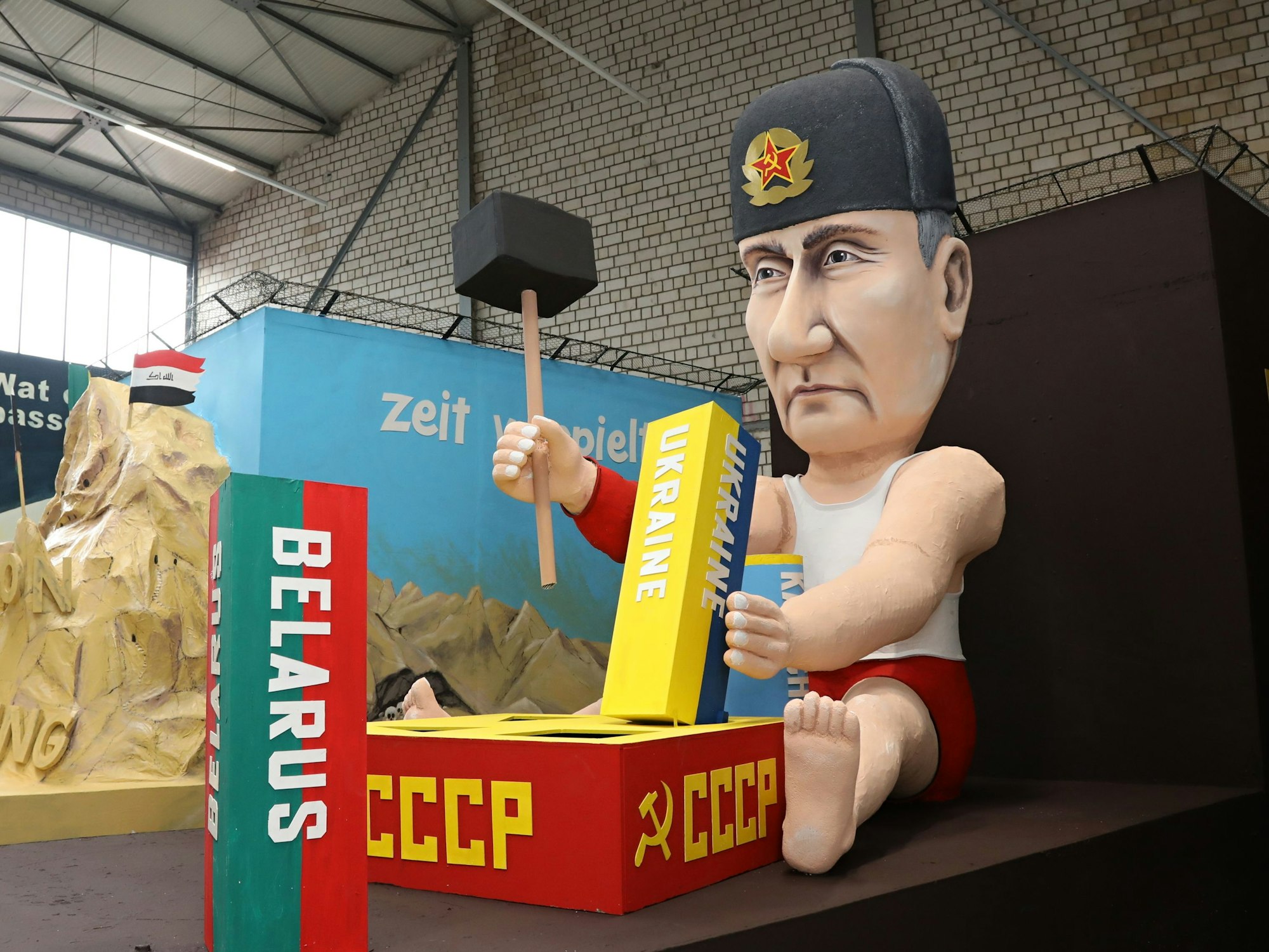 Pappfigur Wladimir Putin spielt mit einem Hammer