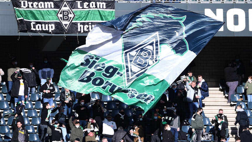 Fans von Borussia Mönchengladbach, hier zu sehen am 12. Februar 2022 im Borussia-Park beim Bundesliga-Duell gegen den FC Augsburg. Die Fans schwenken eine große Fahne.