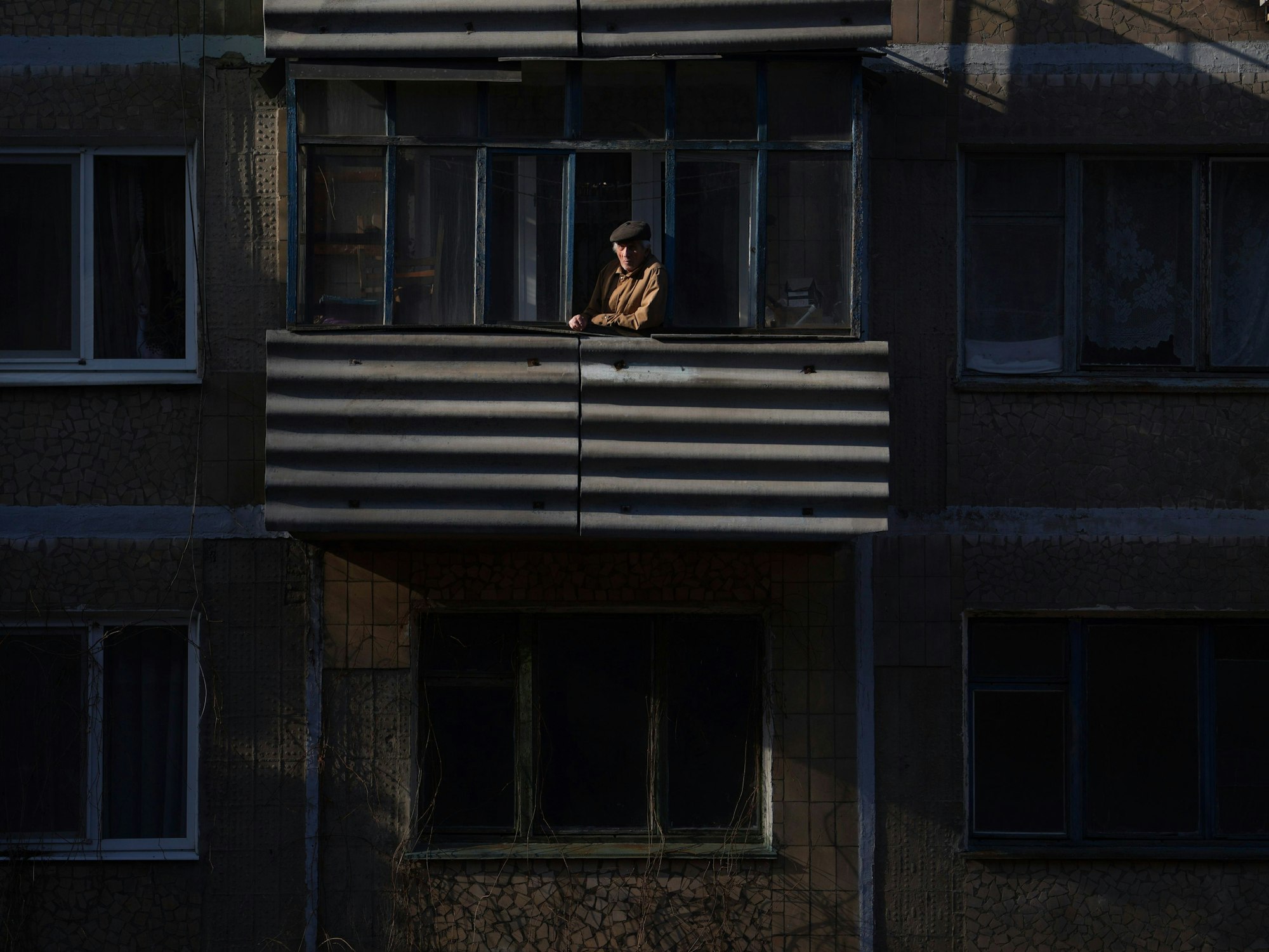 23.02.2022, Ukraine, Novoluhanske: Ein Mann blickt nach einem Artilleriebeschuss bei Sonnenuntergang von einem Balkon. Die Ukraine rüstet sich für einen Krieg mit Russland. Präsident Selenskyj kündigte eine Teilmobilmachung von Reservisten an. Foto: Evgeniy Maloletka/AP/dpa +++ dpa-Bildfunk +++