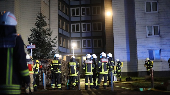Einsatzkräfte der Feuerwehr vor einem Wohnhaus.