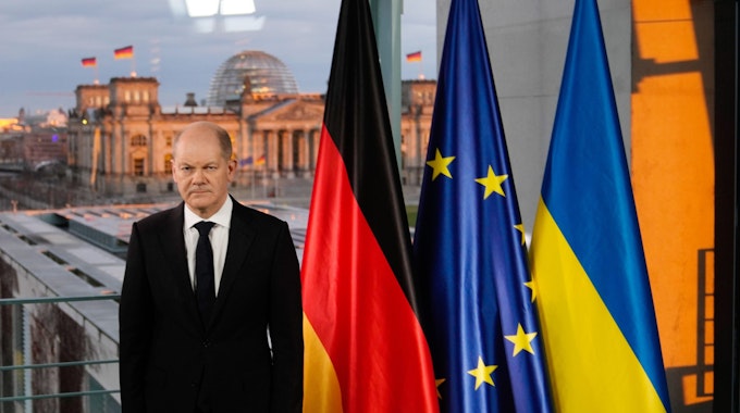 Bundeskanzler Olaf Scholz steht bei einer Fernsehansprache zur Lage zwischen Russland und der Ukraine vor den Fahnen von Deutschland, der EU und der Ukraine.