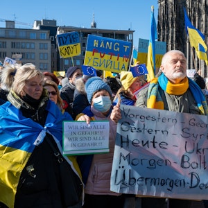 Menschen demonstrieren mit Ukraine-Flaggen gegen den Krieg.