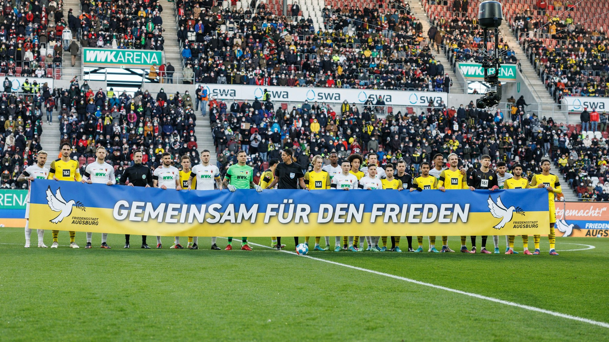Die Spieler des FC Augsburg und von Borussia Dortmund halten gemeinsam ein Banner