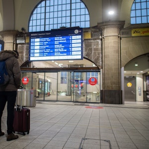 Mann steht im Bahnhof vor einer Anzeigetafel.