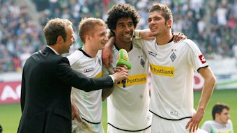 Die ehemaligen Gladbach-Profis (v.r.) Roman Neustädter, Dante und Marco Reus im Gespräch mit Stadionsprecher Torsten Knippertz (l.) am 28. April 2012 im Borussia-Park. Knippertz hält das Stadion-Mikrofon, die Spieler umarmen sich.