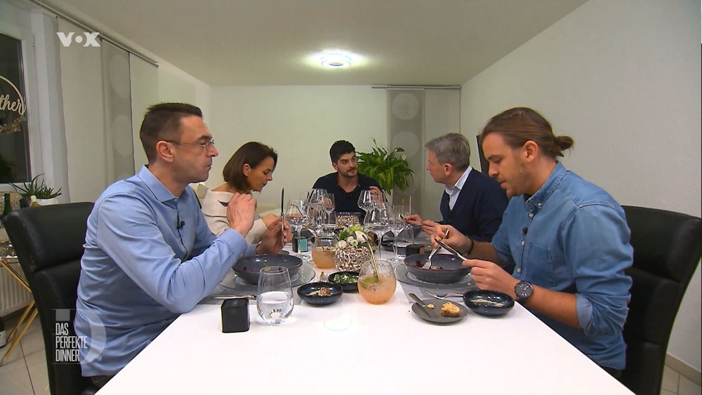 Die „Das perfekte Dinner“-Kandidatinnen und Kandidaten sitzen bei Matthias (m.) am Esstisch.