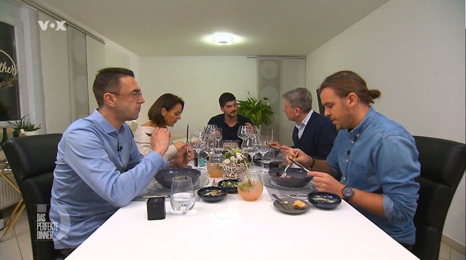 Die „Das perfekte Dinner“-Kandidatinnen und Kandidaten sitzen bei Matthias (m.) am Esstisch.