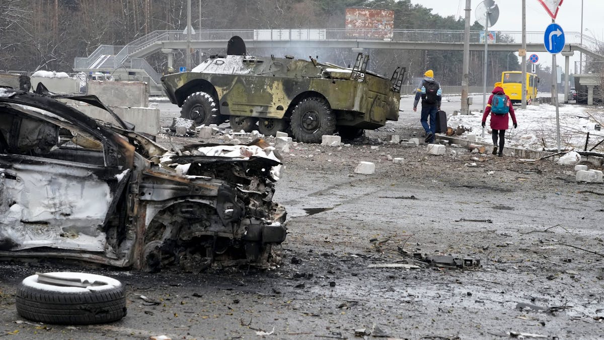 Warum greift Russland die Ukraine an? Menschen laufen am 1. März vor Kiew an völlig zerstörten Militärfahrzeugen vorbei. Seit fast einer Woche herrscht Krieg in der Ukraine. Warum eigentlich?