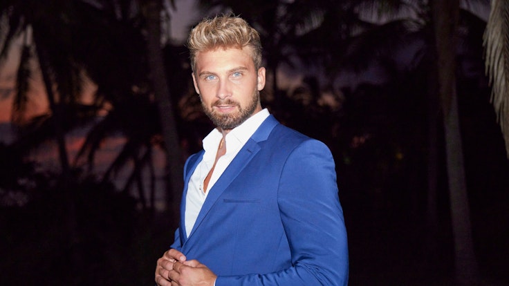 Bachelor Dominik Stuckmann posiert in einem dunkelblauen Anzug für ein Foto