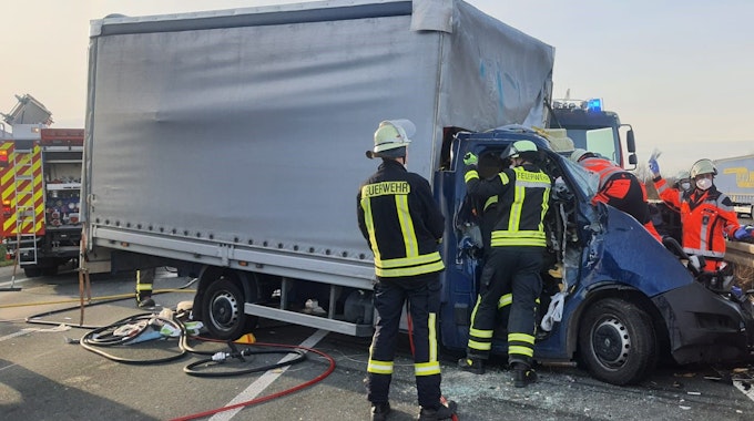 Feuerwehrleute kümmern sich um den Fahrer eines völlig zerstörten Kleinlasters auf der A3 bei Königswinter.
