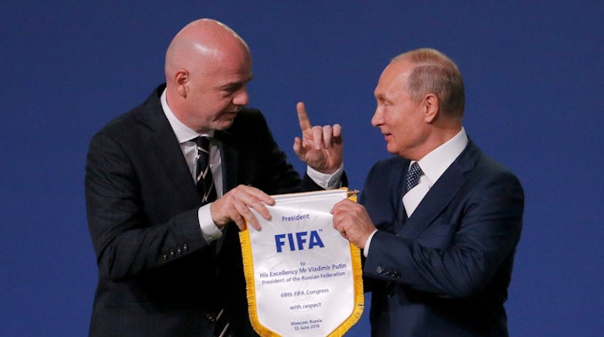 Gianni Infantino übergibt Wladimir Putin einen Wimpel der FIFA.