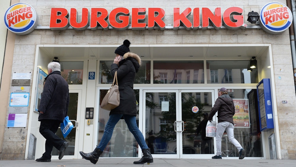 Menschen gehen an Filiale von Burger King vorbei.