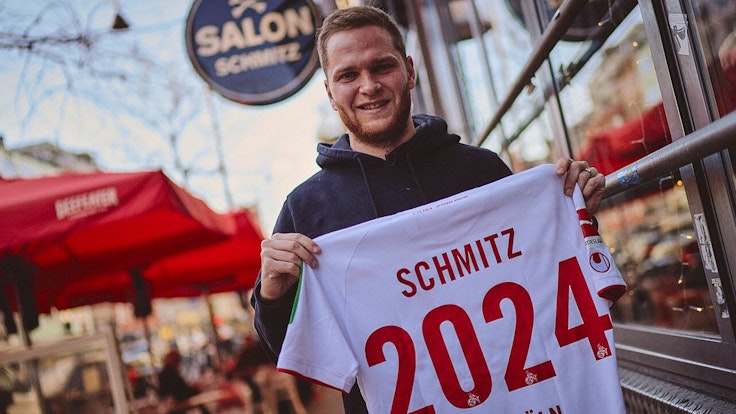 Benno Schmitz präsentiert zur Unterschrift seines neuen Vetrages ein Trikot mit der Aufschrift „Schmitz 2024“