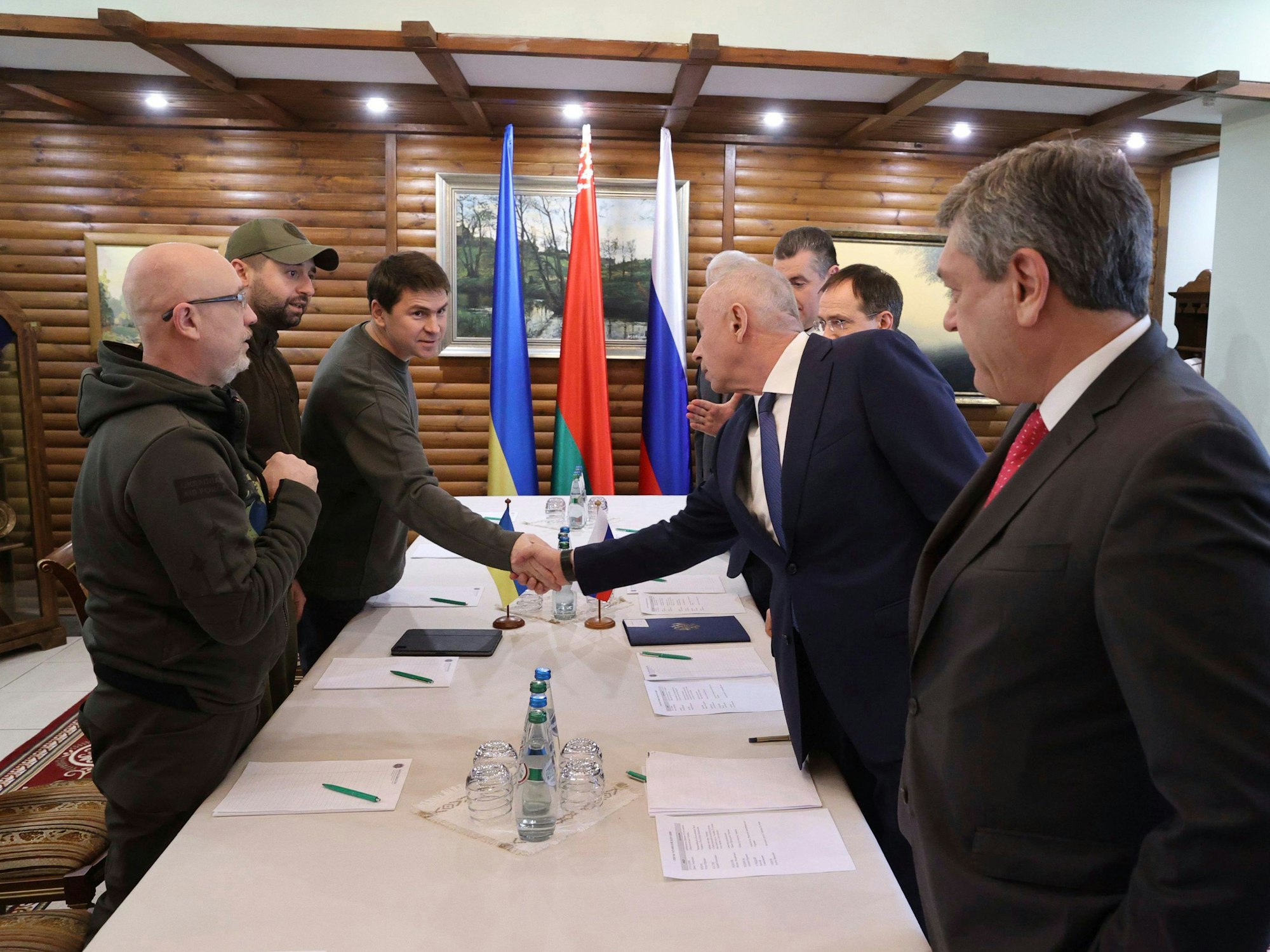 Das von der belarussischen Staatsagentur BelTA verbreitete und von AP zur Verfügung gestellte Bild zeigt die Delegation der Ukraine auf der einen Seite (links) und die Delegation aus Russland auf der anderen. Die Teilnehmer begrüßen sich vor der zweiten Gesprächsrunde.