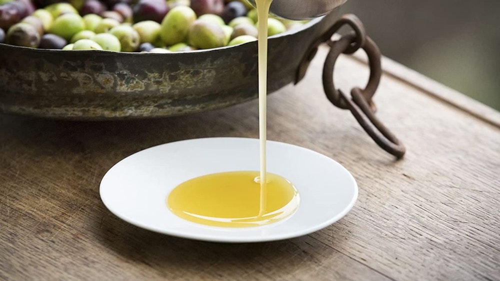 Ein weißer Teller, auf den Olivenöl herunter träufelt.