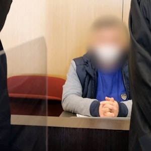 Ein Angeklagter sitzt flankiert von seinen Anwälten auf der Anklagebank des Landgerichts Düsseldorf.