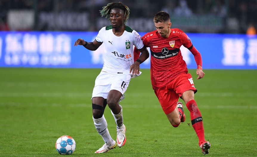 Manu Koné (l.) von Borussia Mönchengladbach im Duell mit Atakan Karazor (r.) vom VfB Stuttgart während des Bundesliga-Hinspiels am 16. Oktober 2021 im Borussia-Park. Beide Akteure kämpfen um den Ball.