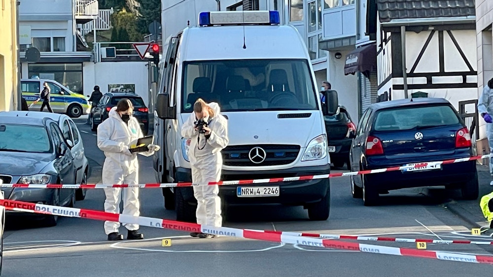 Die Kreuzherrenstraße in Bonn ist mit Polizei-Flatterband abgesperrt, zwei Beamtinnen sichern Spuren. Ein Einsatzfahrtzeug der Polizei steht an der Absperrung.
