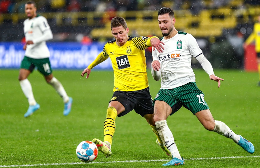 Der Ex-Gladbacher Thorgan Hazard (l.), hier im Trikot von Borussia Dortmund, liefert sich während des Bundesliga-Duells (20. Februar 2022) gegen Borussia Mönchengladbach einen Zweikampf mit Ramy Bensebaini (r.) im Signal-Iduna-Park. Beide Spieler wollen den Ball erobern.