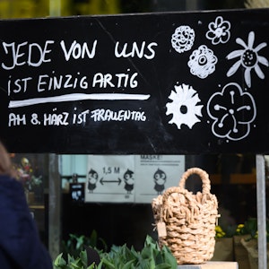 Ein Schriftzug „Jede von ist einzigartig - Am 8. März ist Frauentag“ steht auf einem Schild vor einem Blumenladen.