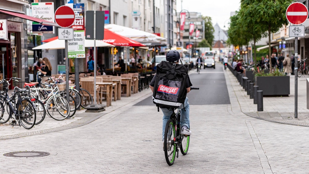 Ein Fahrer des Lieferdienstes Gorillas ist am 20. August 2021 in der Kölner Südstadt unterwegs. In diesem Fall entgegengesetzt der Einbahnstraße, aber das Schild weist darauf hin, dass es erlaubt ist.