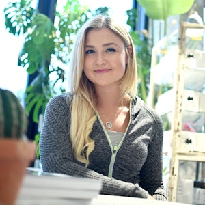 Influencerin Sophia Thiel, hier am Rande der Vorstellung der Sixx-Sendung „Fitness Diaries“ im August 2017, sitzt an einem Tisch und lächelt in die Kamera.