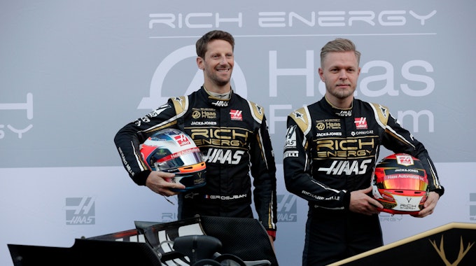 18.02.2019, Spanien, Montmelo: Die Fahrer Kevin Magnussen aus Dänemark (r) und Romain Grosjean aus Frankreich lassen sich mit dem neuen Haas F1-Auto während einer Präsentation auf der Rennstrecke Barcelona Catalunya in Montmelo, außerhalb von Barcelona fotografieren.