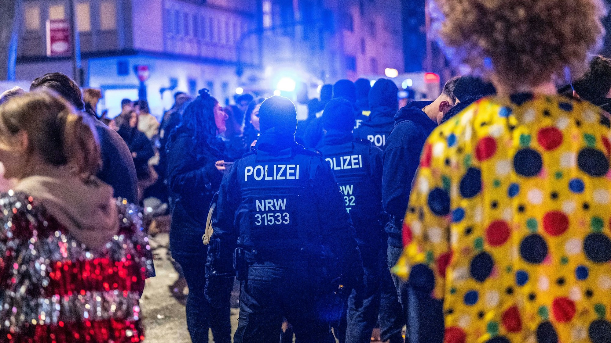 Polizisten kontrollieren das Partygeschehen von Karnevalisten auf der Zülpicher Straße in Köln.