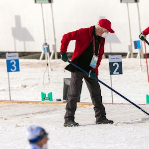 Helfer präparieren bei den Paralympics die Schneefläche am Schießstand im Biathlonstadion.