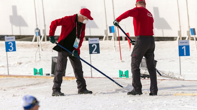 Helfer präparieren bei den Paralympics die Schneefläche am Schießstand im Biathlonstadion.