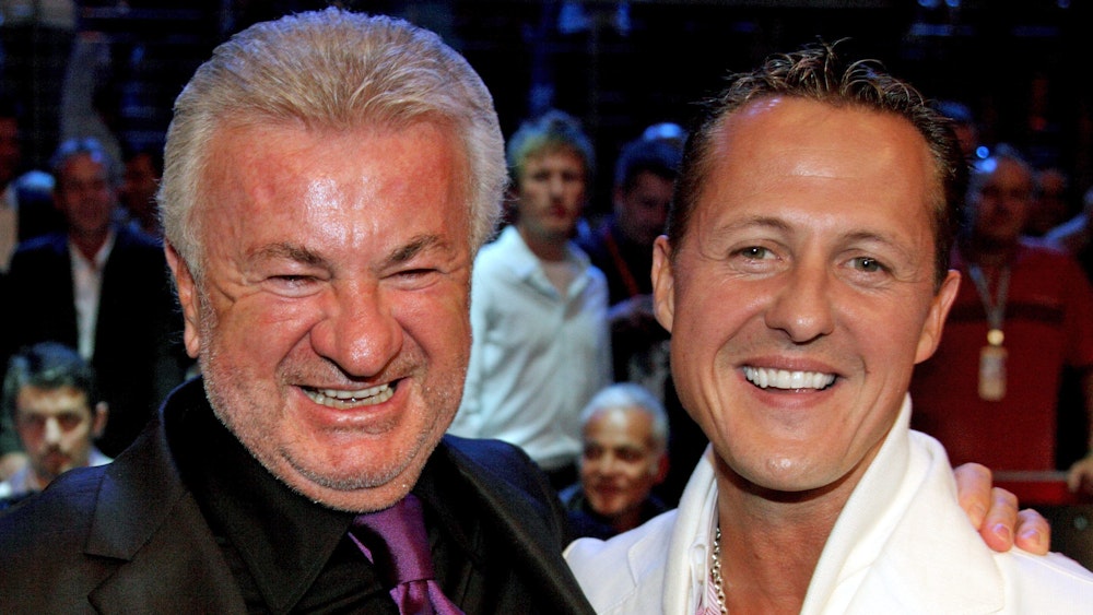Willi Weber posiert mit Michael Schumacher vor einem Box-Kampf von Felix Sturm am Nürburgring.