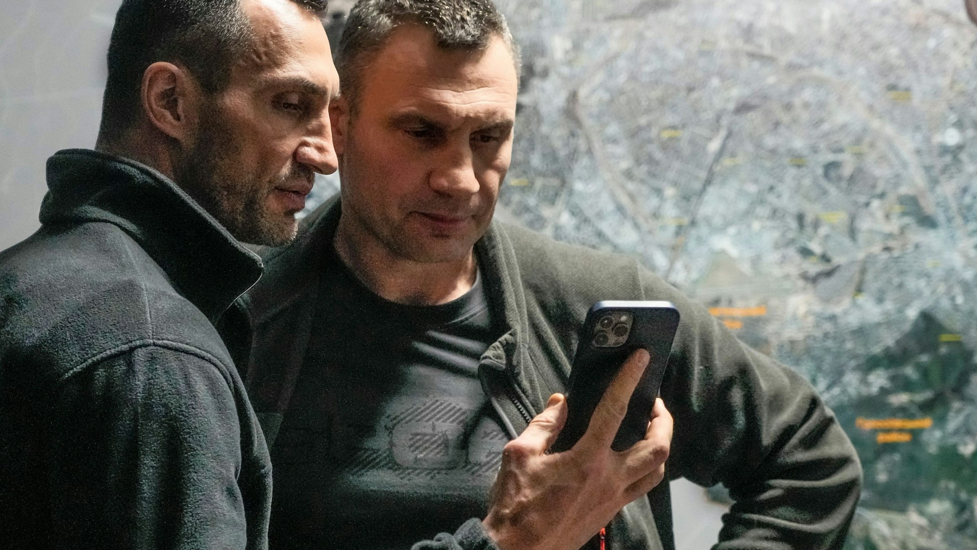 Vitali Klitschko (r), Bürgermeister von Kiew und ehemaliger Box-Profi, und sein Bruder Wladimir Klitschko, ebenfalls ehemaliger Box-Profi, schauen auf ein Smartphone im Rathaus in Kiew.